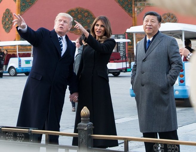 President Donald Trump and Melania Trump in China, pointing toward the distance, General Secretary Xi Xinping looking on.