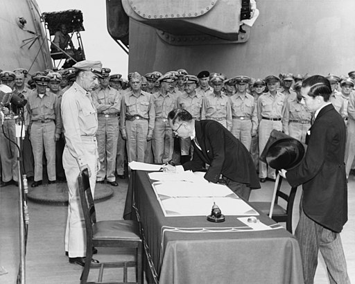 Japanese Foreign Minister Mamoru Shigemitsu signs the Instrument of Surrender on behalf of the Japanese Government, on board USS Missouri (BB-63), 2 September 1945. Lieutentant General Richard K. Sutherland, U.S. Army, watches from the opposite side of the table. Foreign Ministry representative Toshikazu Kase is assisting Mr. Shigemitsu. Photograph from the Army Signal Corps Collection in the U.S. National Archives.